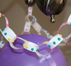 a purple balloon with white and multicolored streamers hanging from it's side