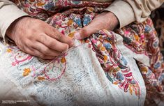 the hands of an old woman are stitching something