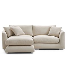 a white couch with pillows on it and a footstool in front of it