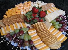 an assortment of cheeses, crackers and fruit on a platter with strawberries