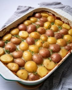 a casserole dish filled with potatoes and garnished with herbs