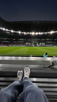 a person's feet resting on the edge of a bench at a soccer stadium