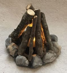 a fire pit made out of logs and rocks on the ground with a lit candle in it