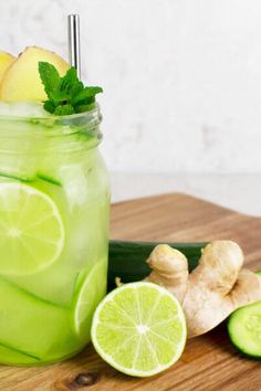 a mason jar filled with cucumber, lemon and lime slices on a cutting board