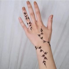 a woman's hand with tattoos on it, and the fingers are decorated with leaves