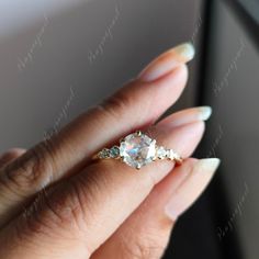 a woman's hand holding an engagement ring with three stones on the middle finger