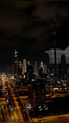 an aerial view of a city at night with lights on and cars driving down the road