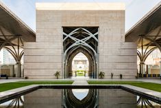 the reflection of an arch in water at the entrance to a building with arches and columns