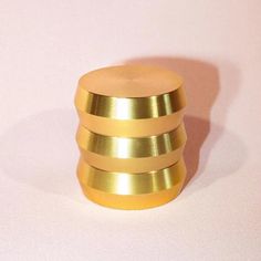 a stack of gold rings sitting on top of a white table next to a pink wall