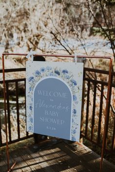 a welcome sign on a wooden deck near some water and trees in the background, with a quote written below it