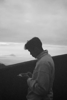 a man standing on top of a hill looking at his cell phone in the dark