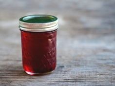 a jar filled with red liquid sitting on top of a wooden table