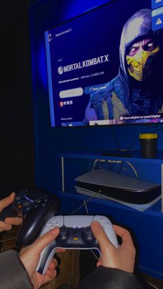 two people playing a video game in front of a flat screen tv on a blue wall