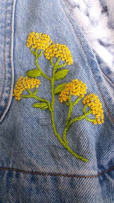 a pair of jeans with yellow flowers embroidered on them