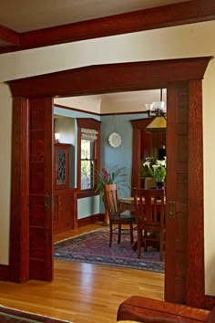 an open door leading to a dining room and living room with blue walls, wood trimming