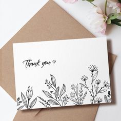 a thank you card with black and white flowers on it, next to a pink flower bouquet