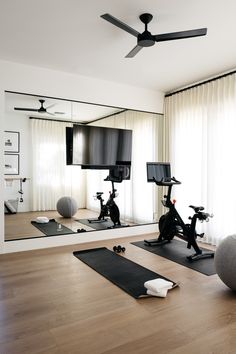 there is a gym with exercise equipment in the room and mirrors on the wall behind it