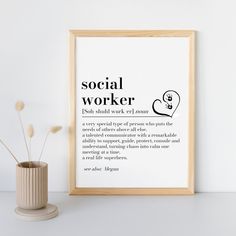 a white vase with some flowers in it next to a framed poster that says social worker