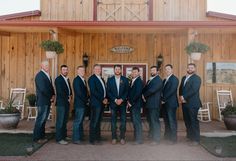 a group of men standing next to each other in front of a wooden building with doors