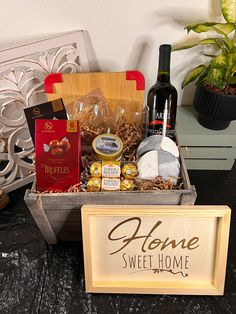 a wine bottle and some snacks in a wooden box next to a sign that says alone sweet home