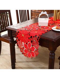 a red table runner with poinsettis on it sitting on a wooden dining room table