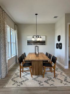 a dining room table with chairs and a rug on the floor in front of it