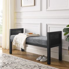 a black bench sitting in front of a window next to a rug and potted plant