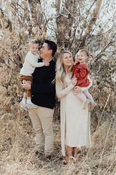 a man, woman and child are standing in tall grass with their arms around each other