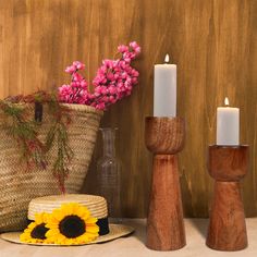 three wooden candlesticks, one with a sunflower and the other with a straw hat