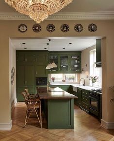 a kitchen with green cabinets and an island in the middle, surrounded by wood flooring