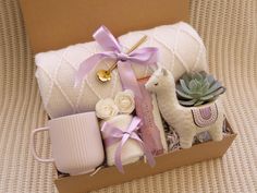 a box filled with baby items sitting on top of a couch next to a cup