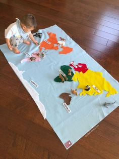 a young boy is playing with toys on a sheet of paper that looks like dinosaurs