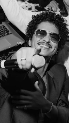 a man wearing sunglasses and holding a microphone in front of a laptop