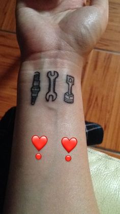 a woman's wrist tattoo with tools and hearts on her left arm, which are red