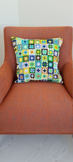 an orange chair with a colorful pillow on it