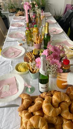 the table is set with croissants, wine and flowers