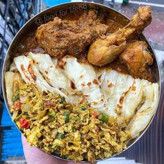 a person holding a metal bowl filled with different types of food and meat on it