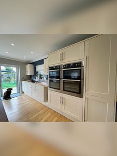 a kitchen with white cabinets and an oven in the center, along with a dog sitting on the floor