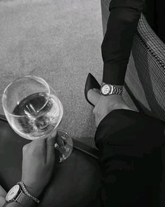 a person holding a wine glass in their hand while sitting on the floor next to a chair