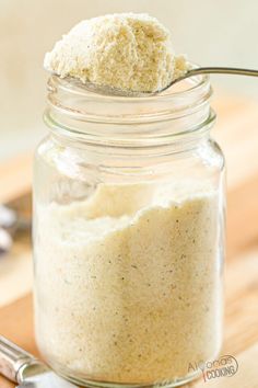 a jar filled with food sitting on top of a wooden table next to a spoon