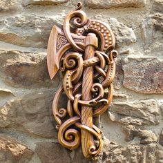 an intricately carved wooden sculpture on the side of a stone wall