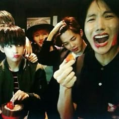 group of young people eating food together in a room with one person sticking out his tongue