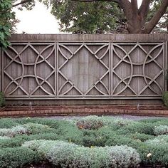 a wooden fence in the middle of a garden with green plants and bushes around it