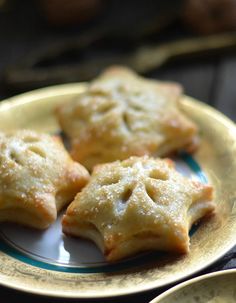 three small pastries on a plate next to two smaller plates with food in them