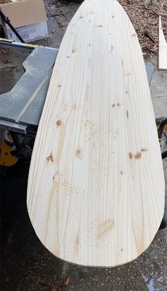 a wooden surfboard sitting on top of a table next to other woodworking tools