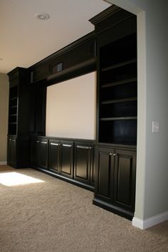 an empty room with black cabinets and a white screen on the wall in front of it