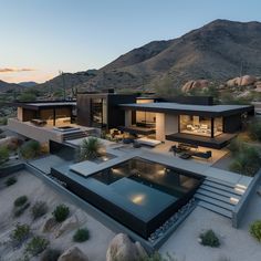 an aerial view of a modern house in the desert with mountains in the back ground