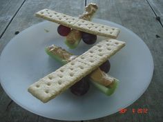 crackers and grapes are arranged on a plate with an airplane shaped piece of bread