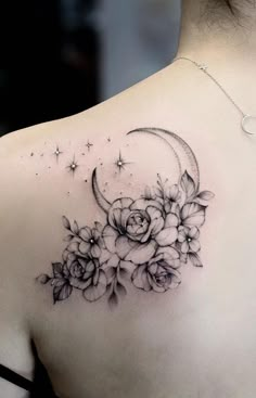 the back of a woman's shoulder with flowers and a crescent tattoo on it