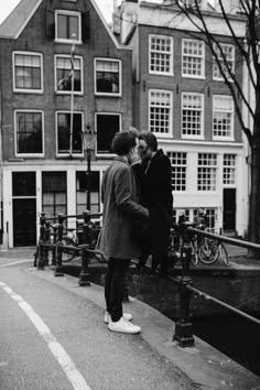 black and white photograph of two people standing on the street with buildings in the background